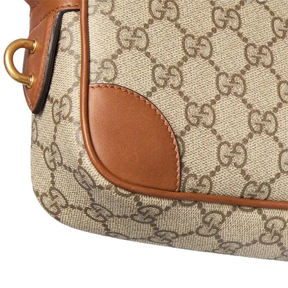 Gucci GG Monogram Crossbody Camera BagBagsGucciDPUS Designer Outlet821216-97838137803624BrownClose-up of Gucci GG Monogram canvas crossbody camera bag with brown leather trim and gold ring.