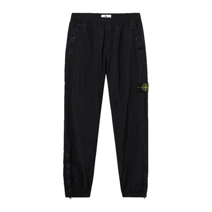 Stone Island black Nylon Metal Econyl crinkled trousers front view with signature compass badge on left leg.
