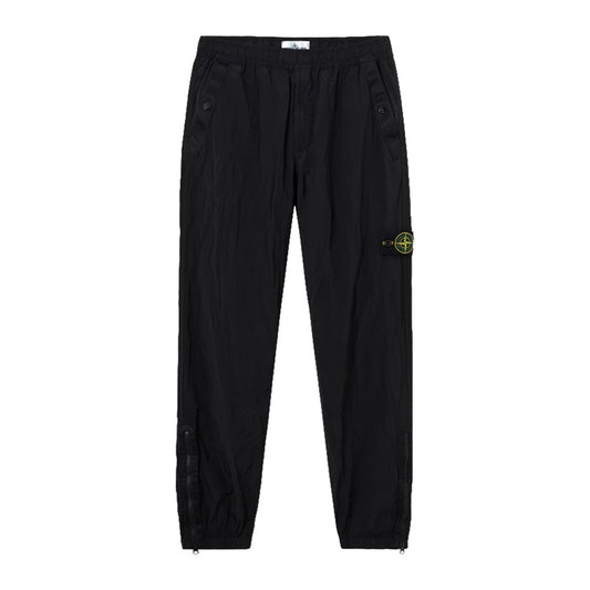 Stone Island black Nylon Metal Econyl crinkled trousers front view with signature compass badge on left leg.